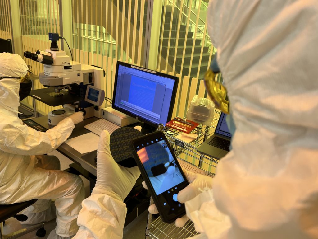 lab photo of someone looking into a microscope and at a wafer